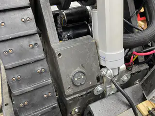 Central linear actuator mounted between the treads above a round chassis indicator.