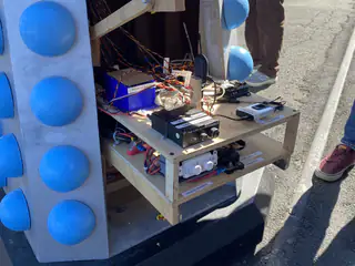Open electronics shelf and wiring visible inside a blue-and-silver robot display.