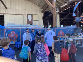 Children gather around two robots during a demonstration inside the Maker Faire hangar.
