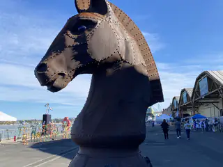 Monumental riveted metal horse head sculpture stands against a clear blue sky.