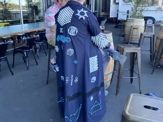 Long black coat decorated with mathematical, scientific, and geometric symbols viewed from behind.