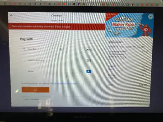 Computer monitor displays Maker Faire checkout payment options and an order total.