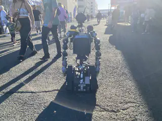 R.O.B. is centered between passing visitors, its articulated arms lowered beside the treads.