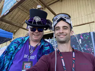 Orbitus exhibitor takes a selfie with an attendee wearing a decorated top hat and goggles.