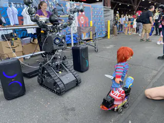 Tracked R.O.B. faces a small red-haired character figure riding a wheeled platform.