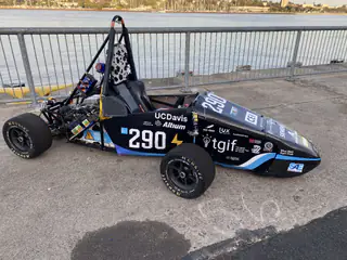 Black UC Davis Formula-style race car numbered 290 displayed beside the waterfront railing.