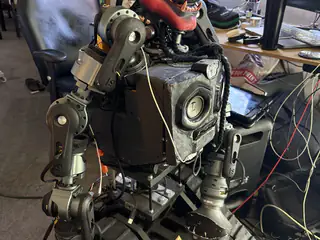 R.O.B.’s black torso, articulated arms, and tracked base amid workshop cables.