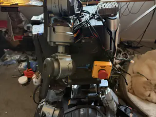 Right-side torso view showing a gray arm joint, bundled cables, and red emergency stop button.