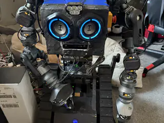 Front full-body view of R.O.B. with one arm angled inward beside its tracked base.