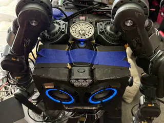 Tighter overhead view centering R.O.B.’s blue speaker eyes, shoulder motors, and taped upper housing.