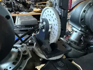 Close side view of intermeshing gray gears mounted between R.O.B.’s shoulder joints.