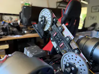 Wider side view of the vertical servo bracket and paired gears above R.O.B.’s upper body.