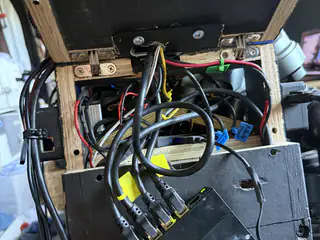 Open rear electronics bay packed with black cables, connectors, circuit modules, and wooden supports.