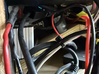 Close-up beneath the chassis showing thick red and black power cables crossing wooden supports.