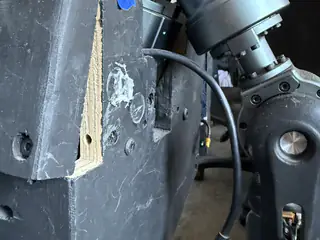 Arm joint mounted beside a rough rectangular opening cut into the black wooden chassis.