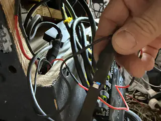 Hand holding a labeled black connector among red, black, and braided cables inside the chassis.