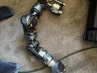 Detached articulated robot arm laid in a curved shape across gray carpet.