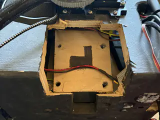 Empty rectangular wooden compartment exposed within the robot’s black body shell.