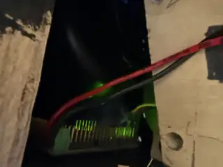 Ethernet cable plugged into a port with green status lights behind a black wooden panel.