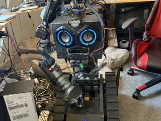 Full frontal view of R.O.B. standing on its tracked base in a cluttered workshop.