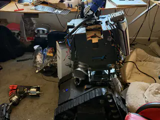 Rear view of R.O.B.’s open black chassis with loose wiring and a detached arm on the floor.