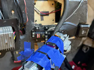 Close front view of a blue-taped arm mechanism aligned with the open wooden chest cavity.