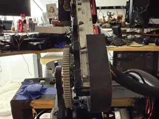 Side profile of the tall central drive assembly with stacked gears and black support plates.