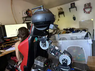 Rear three-quarter view of R.O.B. beside a seated person, with the camera head and arm joints visible.