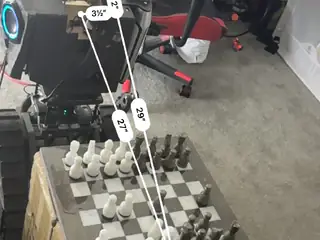Robot and chessboard annotated with white measurement lines showing arm reach, board width, and distances.