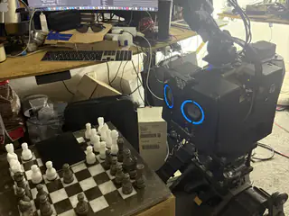 Closer front-side view of R.O.B.’s blue speaker face beside chess pieces in the foreground.