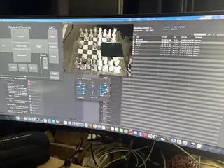 Monitor displaying a software interface with a live chessboard view, controls, and tabular data.