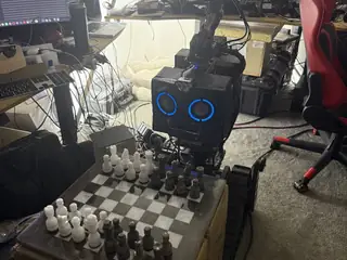 R.O.B. studies a chessboard in the workshop with blue ring lights glowing on its chest.