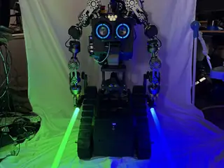 Front portrait of R.O.B. holding a glowing green lightsaber and a glowing blue lightsaber.
