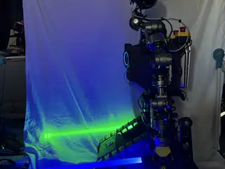 Side profile of R.O.B. framed by crossed blue and green lightsaber glow.