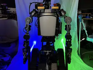 Rear portrait of R.O.B. showing its computer enclosure, articulated arms, and blue-green lighting.