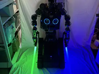 Dramatic full-length portrait of R.O.B. with green and blue lightsabers illuminating both sides.