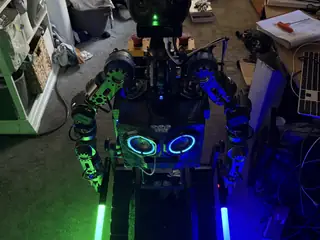 High three-quarter view of R.O.B. holding green and blue lightsabers beside its tracked base.