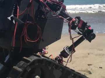 Close-up of R.O.B.'s arm and tracked base at the beach