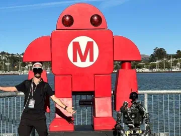 A person and R.O.B. beside the Maker Faire robot at Mare Island